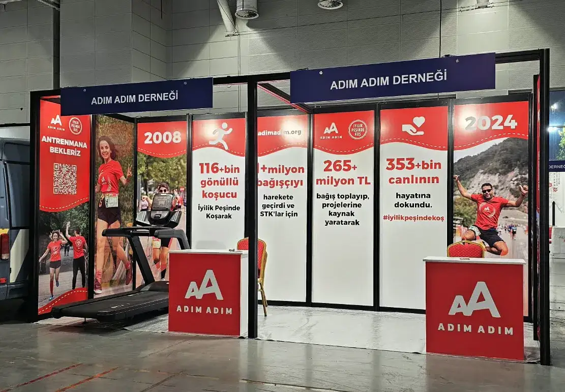 Adım Adım Derneği için kurulmuş paket stand; alınlıkta marka adı, dijital baskılı yan paneller ve baskılı banko