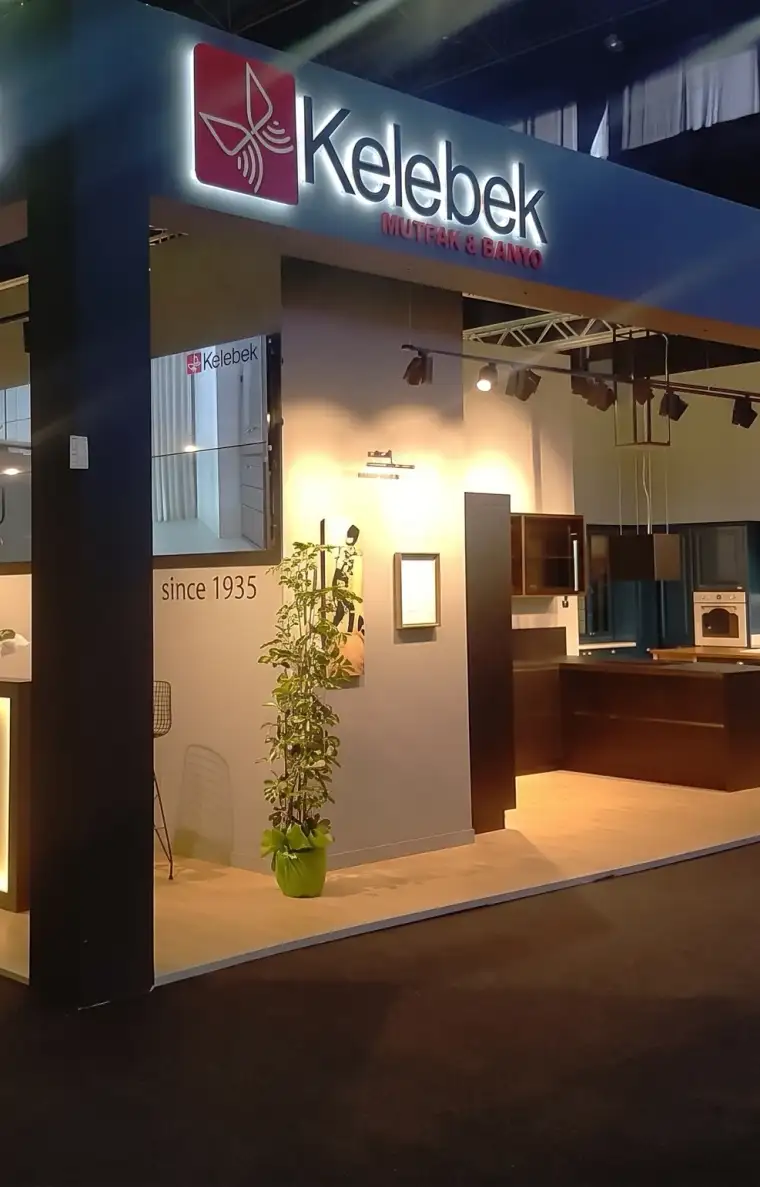 Kelebek Mutfak & Banyo için kurulmuş ahşap fuar standı; arkadan aydınlatmalı lacivert alınlık, ışıklı marka tabelası ve içeride mutfak vitrinleri.
